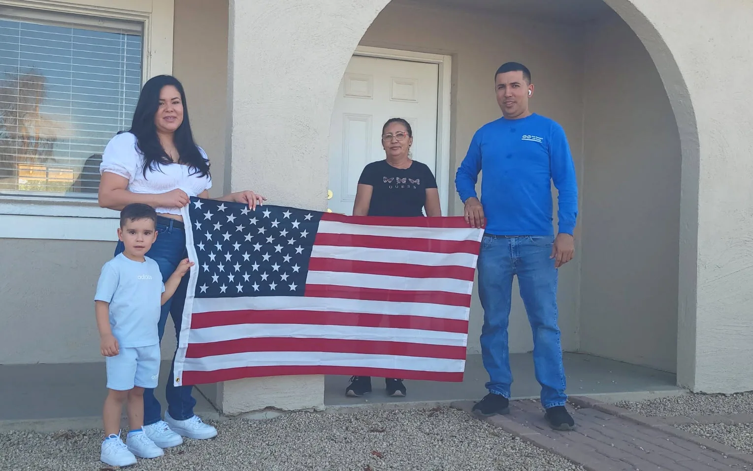 A family with the American flag on the porch of their new home.