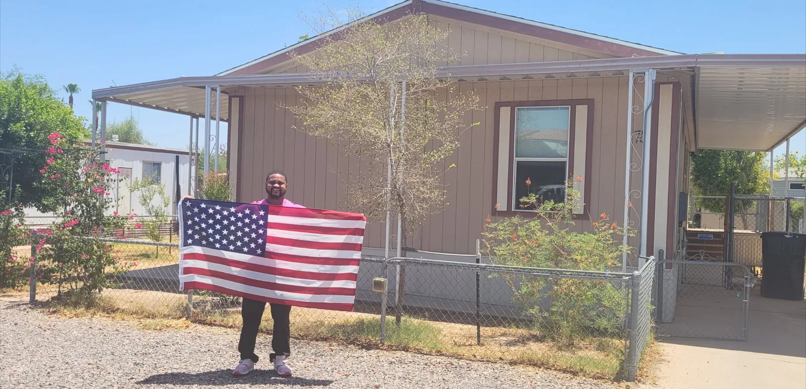A proud new homeowner holding the American flag in front of his home.